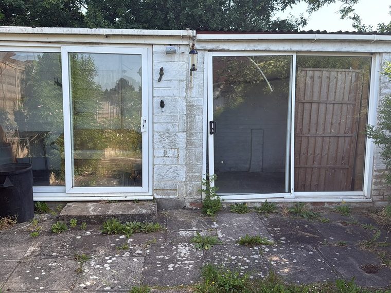 Old outbuilding with glass doors before demolition